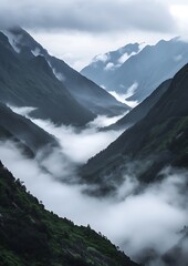 A peaceful mountain valley covered in thick fog, with low-lying clouds resting in the valleys between the peaks, creating a layered, surreal visual effect.