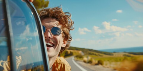 A young man enjoys a road trip with a joyful smile, feeling the wind through his hair while driving along a scenic coastal highway under a clear blue sky