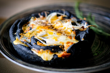 Artisan cheese-stuffed pizza with black crust.