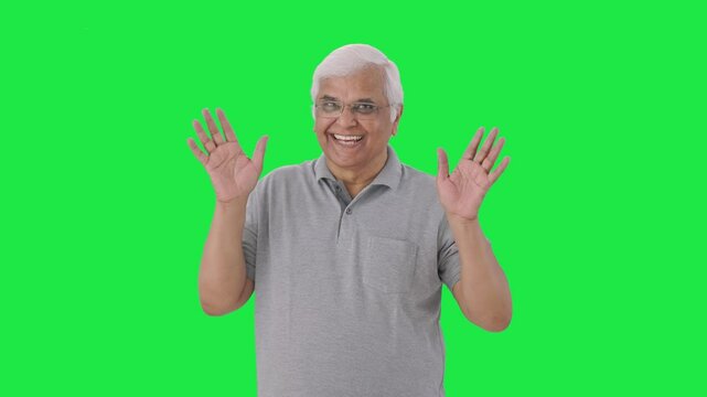 Happy Indian old man saying hello and waving Green screen