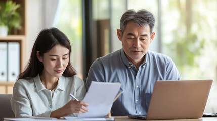 Obraz premium Japanese couple planning finances with documents and laptop