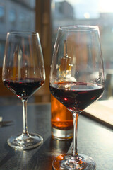 Two wine glasses with red wine and a bottle with chili oil on a table in a restaurant in backlight with reflections