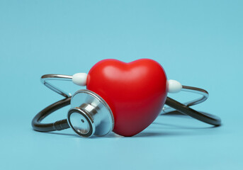 Red heart shape exercise ball with doctor physician's stethoscope on blue background, hospital life...