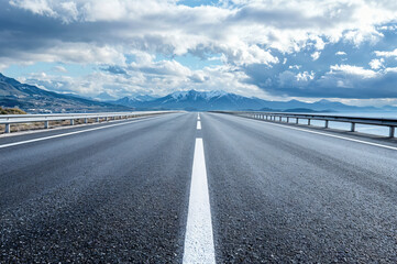 Fototapeta premium Empty asphalt highway leading to snowy mountains