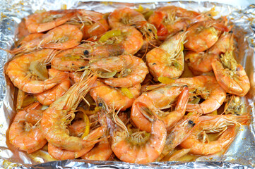 Pile of unpeeled grey shrimps cooked on hot steam and grilled with slices of onion, garlic cumin, slices of colored bell peppers and salt cooked and grilled, seafood cuisine of shrimps crustaceans