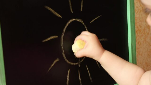 A small child draws with chalk on a blackboard. The child learns to write. Children's education