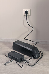 Charging bicycle battery from mains electricity in house. Socket in room with plug switched on....