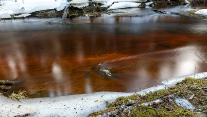small, wild river in spring, calm river flow, ice and snow on the banks of the river, Strikupe, Vaidava, Latvia