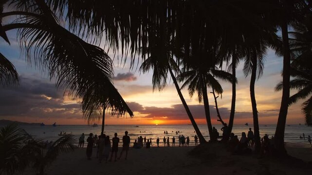 Silhouetted people and palms near sea. Sunset at tropical White beach, Boracay island, Philippines, slow motion 4k