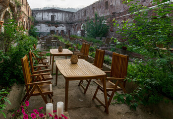 Wooden tables and chairs in an old roofless stable.