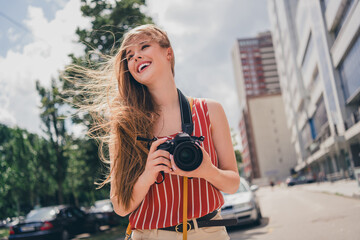 Photo of positive cute girl wear trendy clothes walk city center take picture summer weather outdoors