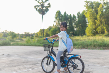 Fototapeta premium A young girl is riding a bicycle with a basket on the front.