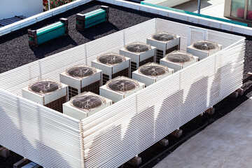 Row of air conditioners are on a roof. Multiple air conditioning units positioned on rooftops....