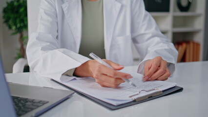 Fototapeta premium Physician hands writing records sitting clinic table with laptop closeup. 