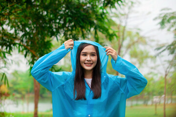 A woman in a blue raincoat is smiling and holding the hood over her head. Concept of happiness and...