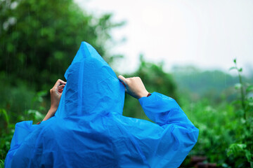A woman in a blue raincoat is standing in a park