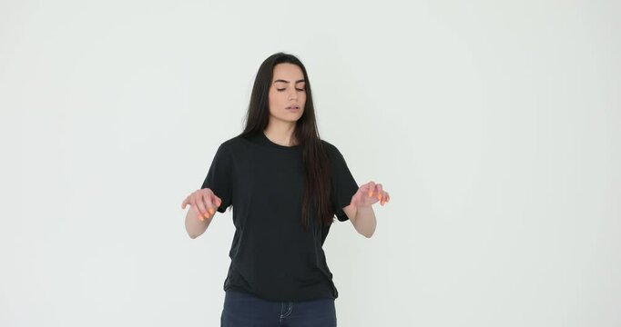 Inspired woman with long loose hair plays imaginary piano on white background. Talented female musician shows skills standing in empty room