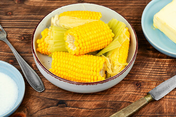 Juicy sweet boiled corn or maize on rustic wooden table.