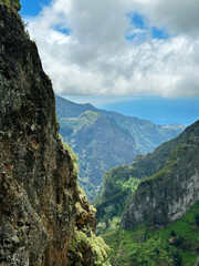 Fototapeta premium Hiking mountain trail among rocks and plants with a view of the clouds and gorge