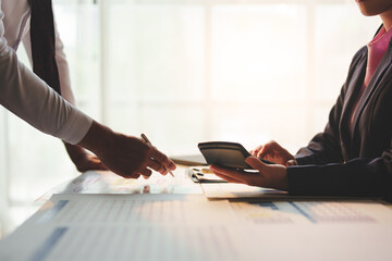 Two businessmen working in finance Online marketing on a laptop. Calculate, analyze, graph investment costs. Real estate and taxes on work table in modern office together.