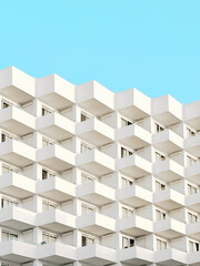 Minimalist photo of resort hotel building with repeating patterns of windows and architectural elements and blue sky in the background