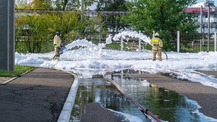 Firefighters in protective clothing use a foam generator to supply foam to extinguish the fire....