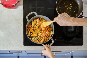Stir-frying vegetables and chicken in a modern kitchen during evening meal preparation
