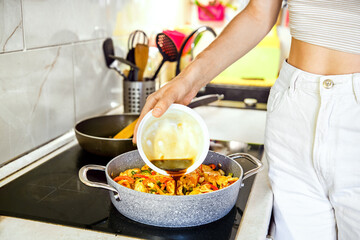 Cooking a vibrant vegetable stir-fry with sauce preparation in a modern kitchen setting