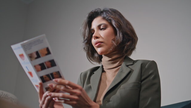 Young woman reading brochure in beauty clinic closeup. Beautiful businesswoman