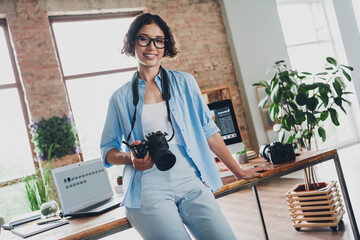 Photo of charming happy camera woman wear shirt smiling shooting photo indoors workplace workstation