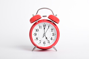 Red alarm clock set at five o'clock isolated on white background. Close-up with clipping path