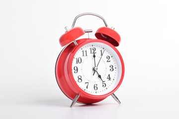 Red alarm clock set at five o'clock isolated on white background. Close-up with clipping path