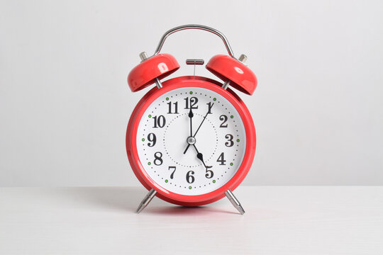 Red alarm clock set at five o'clock on table isolated on white background close-up with clipping path