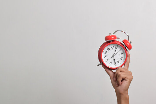 Man holding red alarm clock in hand isolated on white background. Close-up with clipping path