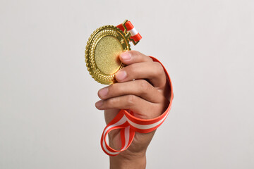 Hand holding gold medal isolated on white background. The winner and successful concept