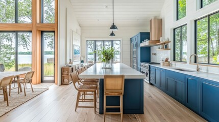 Fototapeta premium Modern kitchen with blue cabinets, white countertop, and large windows overlooking a lake.