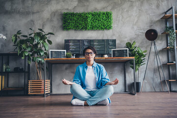 Full body photo of attractive young woman sit floor meditate wear blue shirt modern office...