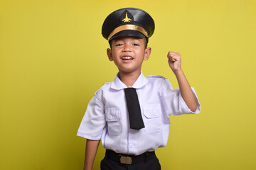 Little Asian boy Airplane pilot isolated on yellow background celebrating a victory in winner position. Little boy dreams of becoming an airplane pilot.