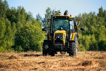 Modern agricultural tractor harvesting grass in the field