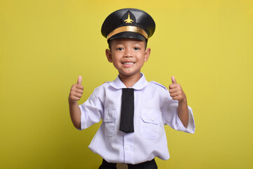 Little Asian boy Airplane pilot isolated on yellow background with thumbs up gesture and smile. Little boy dreams of becoming an airplane pilot