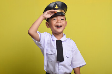 Little Asian boy Airplane pilot salute isolated on yellow background. Little boy dreams of becoming an airplane pilot.