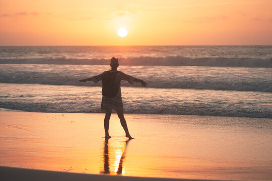 Woman enjoying sunset on sandy beach. Relax and calm on the beach.