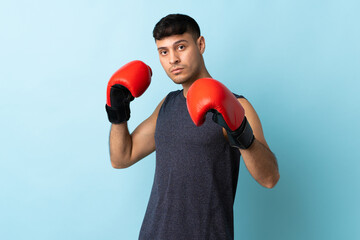 Young Colombian man isolated on blue background with boxing gloves