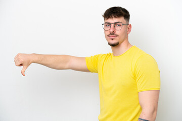 Young caucasian handsome man isolated on white background showing thumb down with negative...