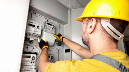 Technician working on a modern electricity power meter station in a building.