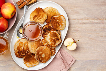 Homemade apple fritters with honey on a large white plate on a wooden table.  Healthy tasty breakfast. Top view. Copy space