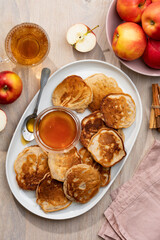 Apple pancakes or fritters with honey on a large white plate on a wooden table. Delicious breakfast. Top view