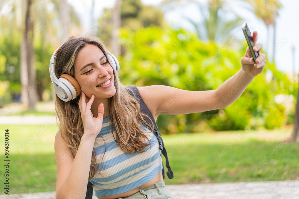 Wall mural young pretty woman at outdoors using mobile phone