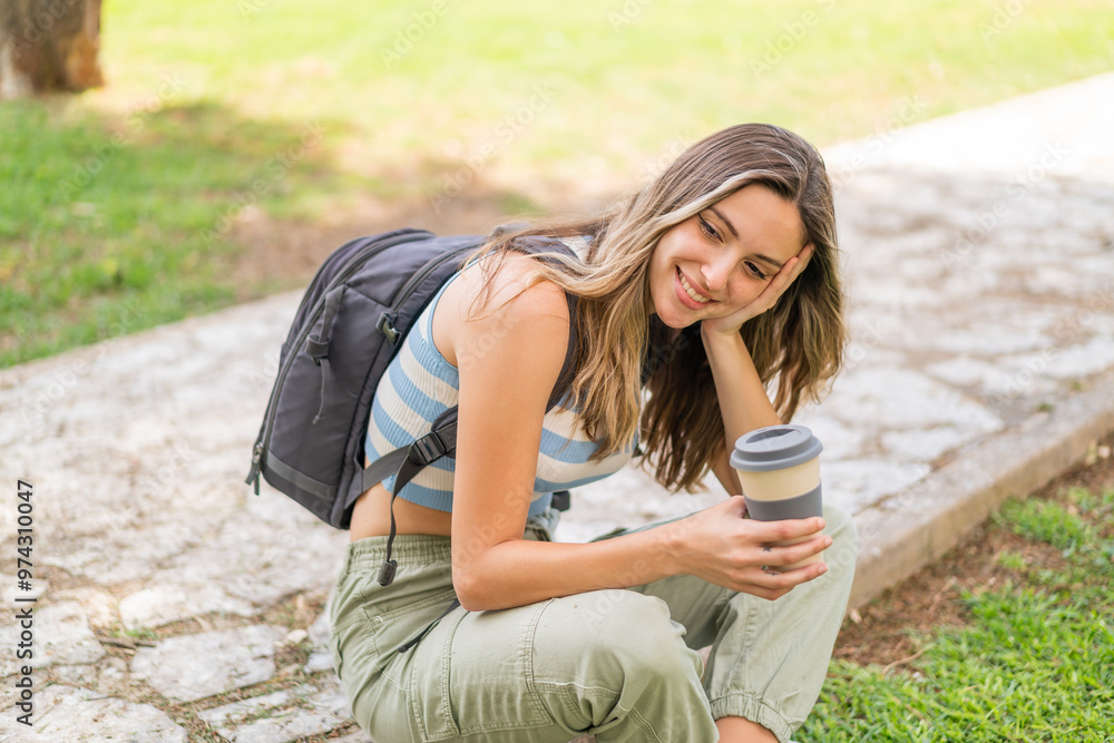 Wall mural Young pretty woman at outdoors holding a take away coffee