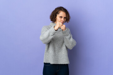 Young English woman isolated on purple background with fighting gesture